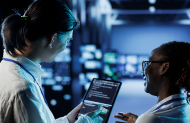 Two cybersecurity professionals analyzing network data on a tablet